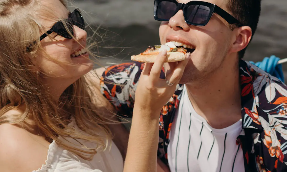 A girl feeding her boyfriend pizza